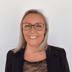 Smiling woman with glasses in a black blazer, professional headshot.